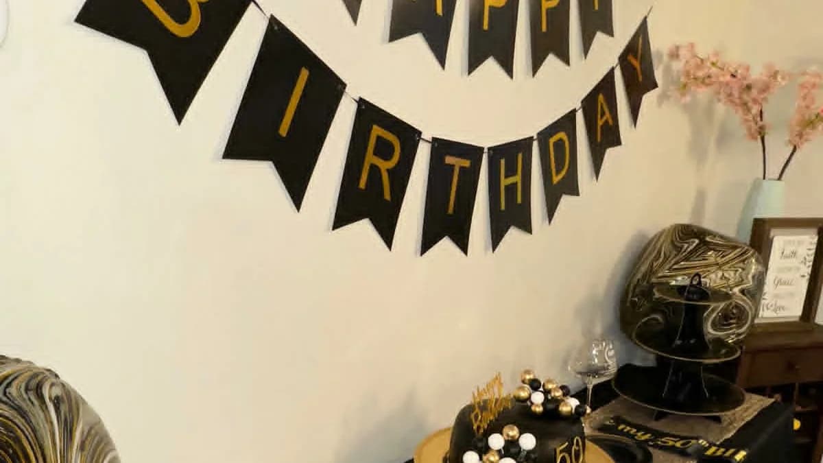 Black and gold birthday dessert table beneath a Happy Birthday banner