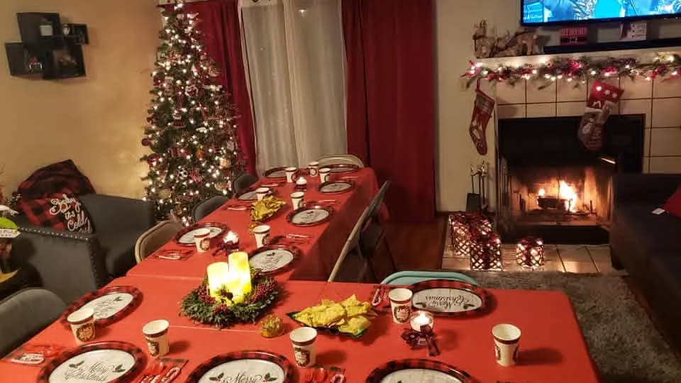 Family Christmas tables prepared beside a decorated tree and fireplace