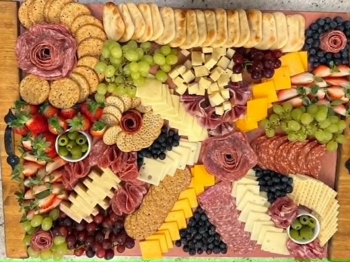 Overhead charcuterie board with fruit, cheese, crackers, and meats